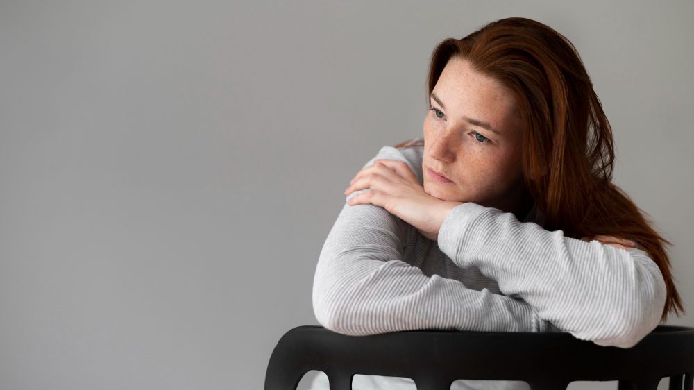 medium-shot-depressed-woman-sitting-chair